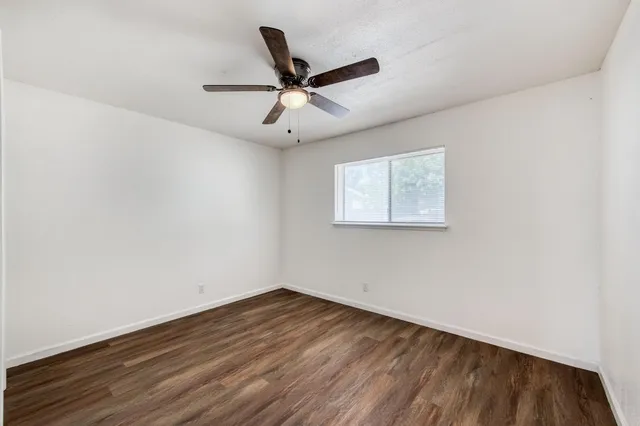 an empty room with wooden floor and ceiling fan