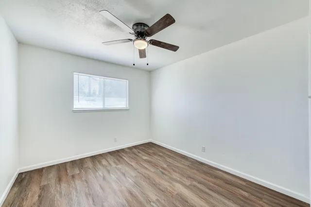 a view of an empty room with window and a ceiling fan
