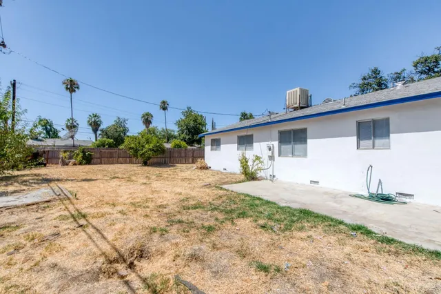 a view of house with backyard and bushes