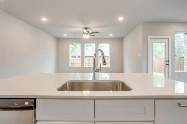 a view of an empty room with kitchen and window