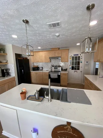a kitchen with stainless steel appliances kitchen island granite countertop a refrigerator a stove a sink dishwasher with a dining table and chairs