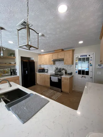 a kitchen with stainless steel appliances granite countertop a stove a sink and a refrigerator