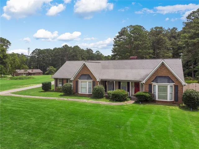 a view of a house with a big yard and large trees