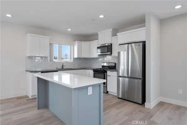 a kitchen with kitchen island a refrigerator sink and cabinets