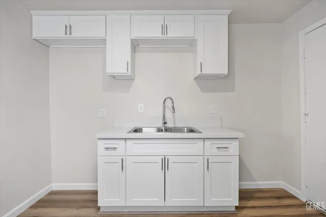 a kitchen with white cabinets and sink