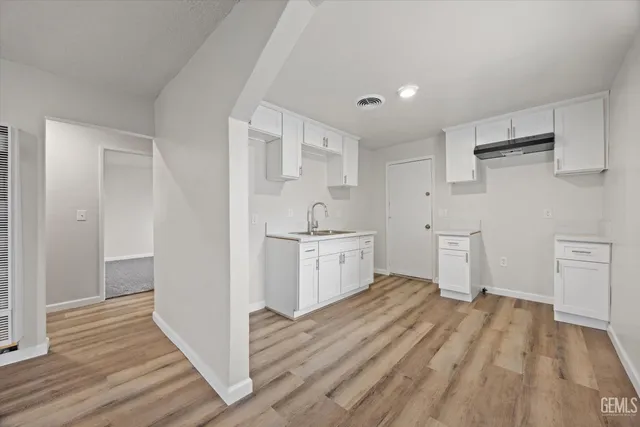 a kitchen with white cabinets and wooden floor