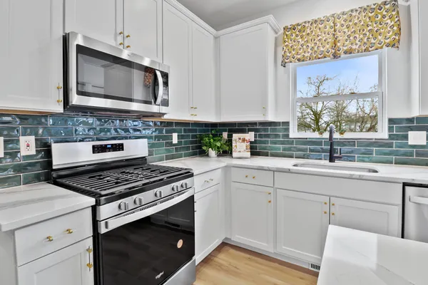 a kitchen with cabinets stainless steel appliances a sink and a window