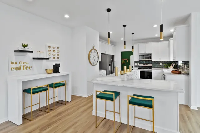 a kitchen with stainless steel appliances granite countertop a stove a refrigerator a oven a sink a stove and white cabinets with wooden floor