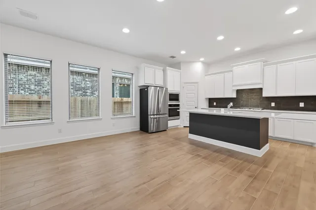 a kitchen with stainless steel appliances a refrigerator sink and white cabinets