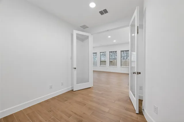an empty room with wooden floor and windows