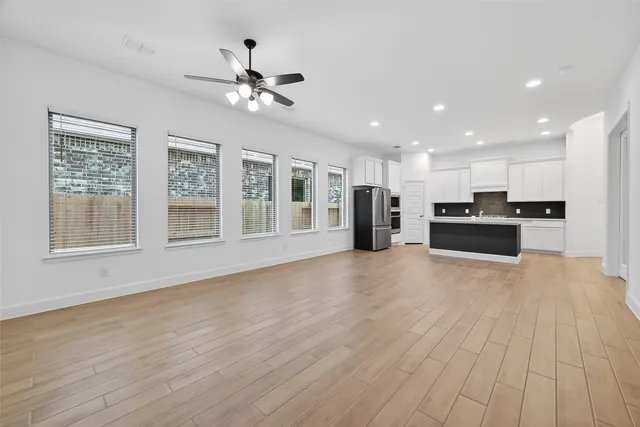 a view of an empty room with kitchen and a window