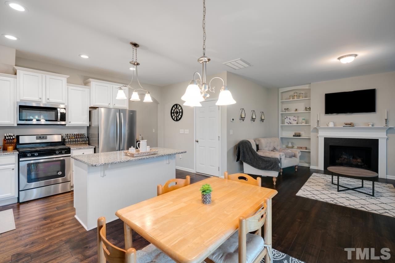 285 Bella Square Smithfield, NC 27577 - Photo 9 of 30 a kitchen with kitchen island a stove a sink a microwave a dining table and chairs