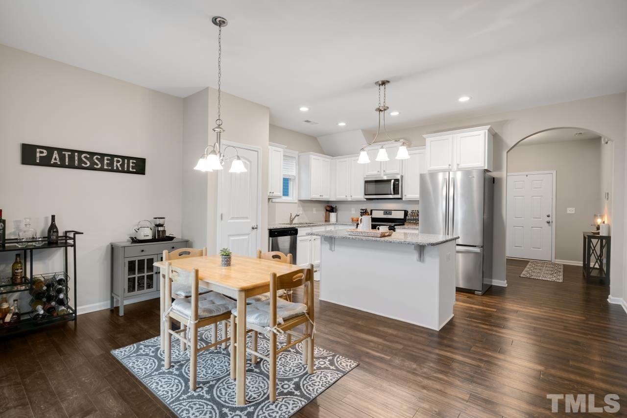 285 Bella Square Smithfield, NC 27577 - Photo 10 of 30 a kitchen with stainless steel appliances kitchen island granite countertop a dining table chairs and white cabinets