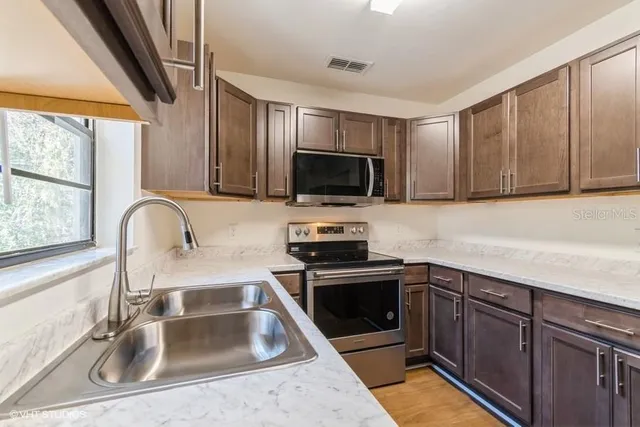 a kitchen with stainless steel appliances granite countertop a sink and a stove top oven