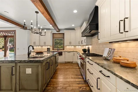 a kitchen with stainless steel appliances granite countertop a sink a stove and a wooden floors