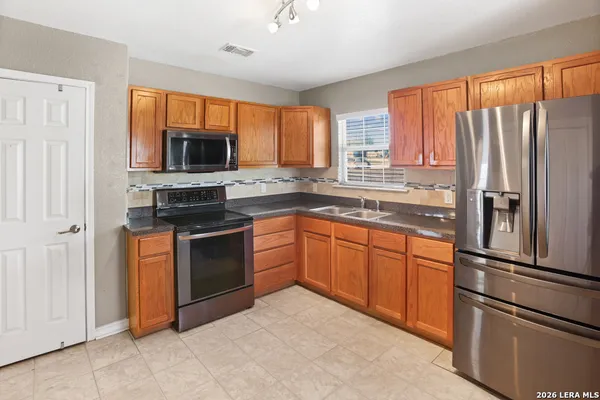 a kitchen with stainless steel appliances granite countertop a refrigerator a stove top oven a sink and dishwasher