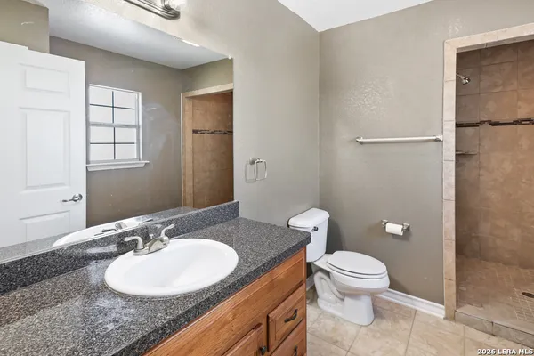 a bathroom with a granite countertop sink toilet a mirror and shower