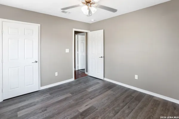 a view of an empty room with window a chandelier fan and wooden floor