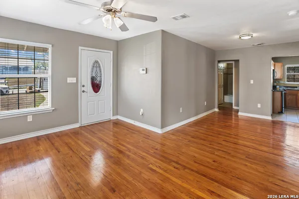 a view of an empty room with window and wooden floor