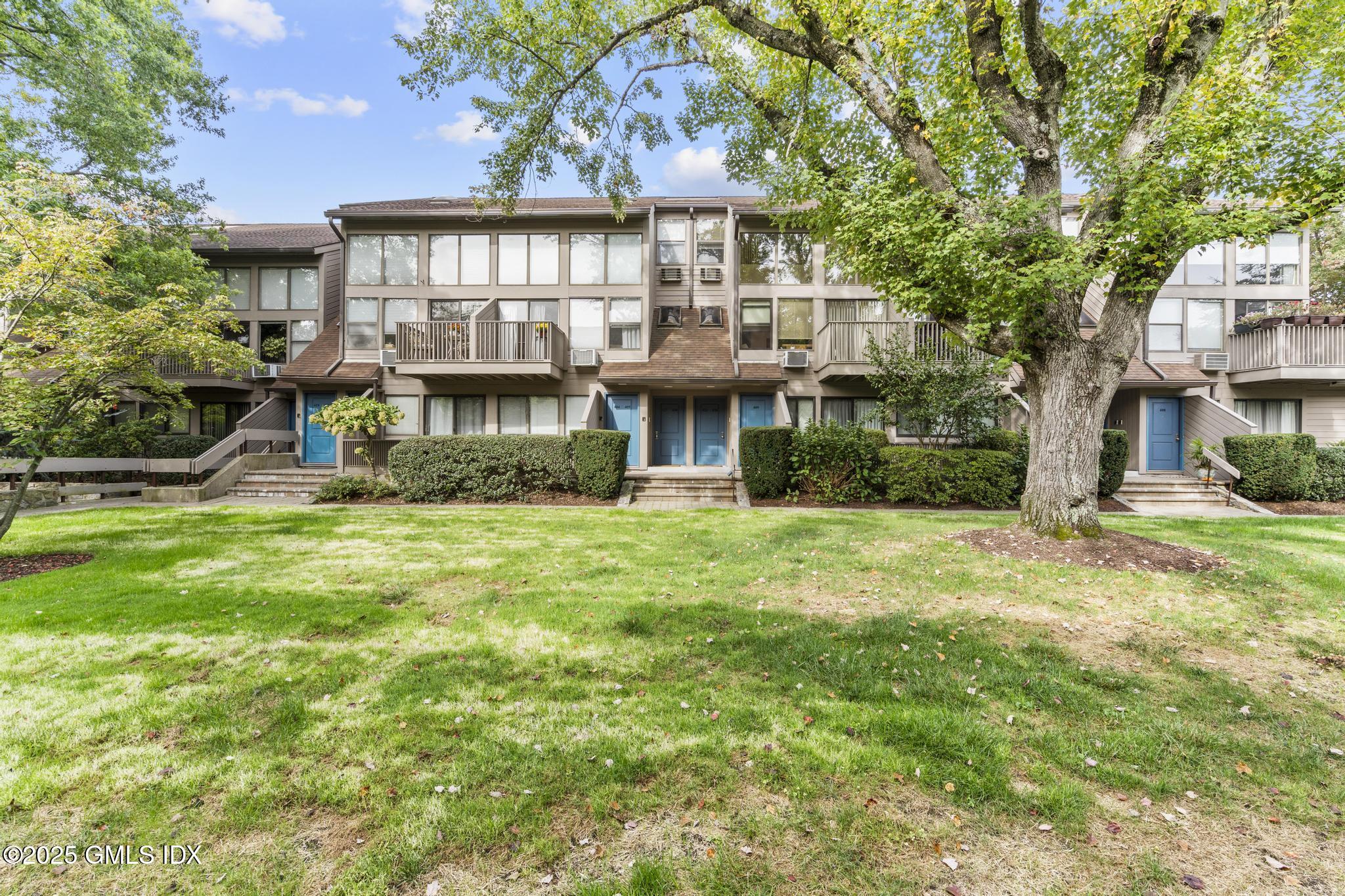 1465 East Putnam Avenue, Unit 421 Riverside, CT 06878 - Photo 26 of 29 a front view of a house with a yard