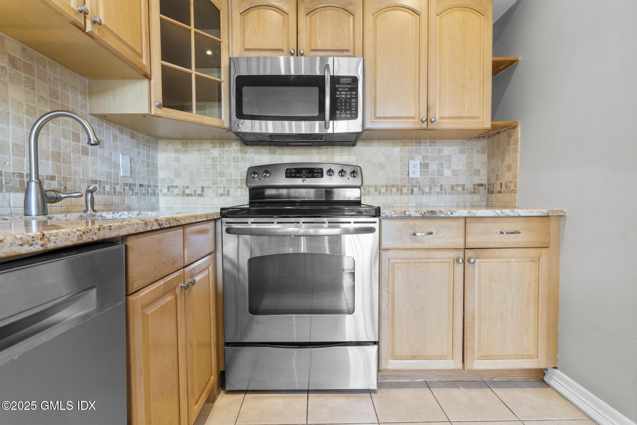 1465 East Putnam Avenue, Unit 421 Riverside, CT 06878 - Photo 9 of 29 a kitchen with stainless steel appliances granite countertop a stove a sink and a microwave