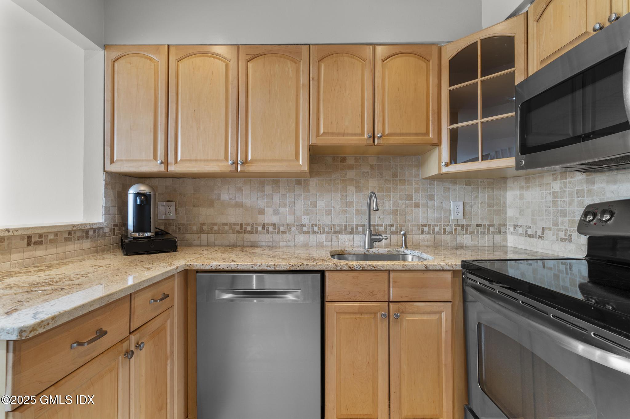 1465 East Putnam Avenue, Unit 421 Riverside, CT 06878 - Photo 10 of 29 a kitchen with stainless steel appliances granite countertop a sink stove and cabinets