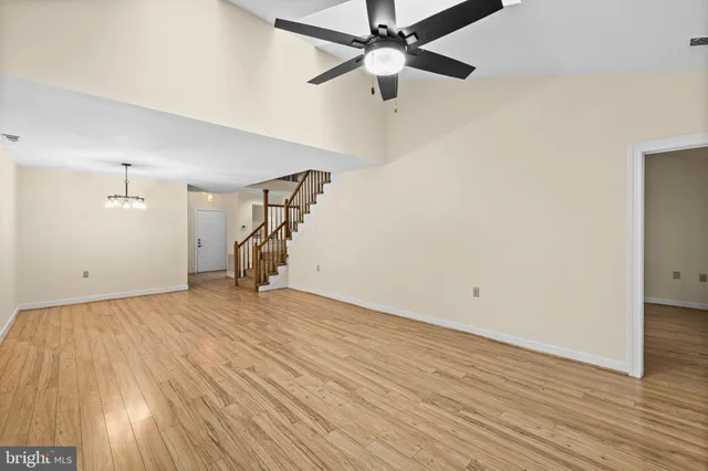 an empty room with wooden floor ceiling fan and windows