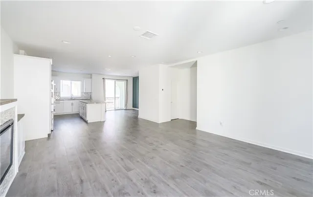 an empty room with wooden floor fireplace and windows