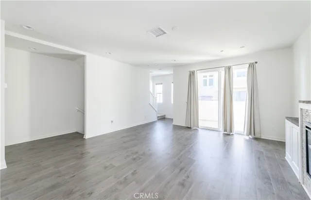 a kitchen with stainless steel appliances a refrigerator a sink dishwasher a stove top oven a refrigerator with wooden floors and white cabinets