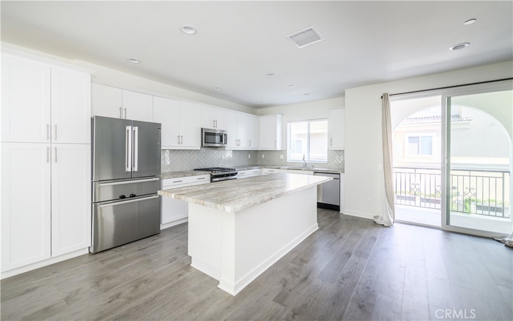 603 Shadowbrook Lake Forest, CA 92610 - Photo 16 of 60 a kitchen with stainless steel appliances a refrigerator a sink dishwasher a stove top oven a refrigerator with wooden floors and white cabinets