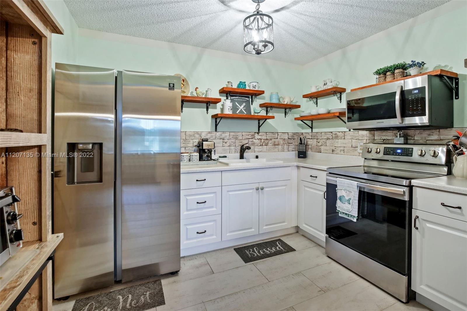 334 Pine Ridge Circle, Unit A2 Greenacres, FL 33463 - Photo 2 of 16 a kitchen with stainless steel appliances a stove a sink and a refrigerator