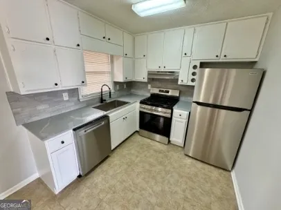 a kitchen with granite countertop a refrigerator sink stove and cabinets