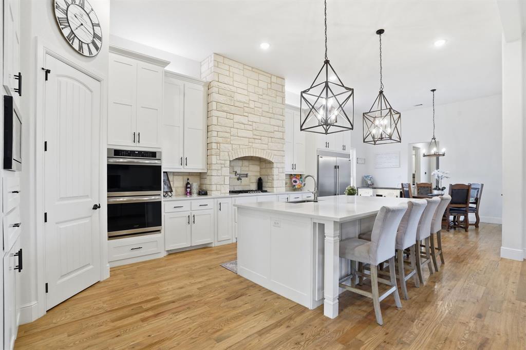 103 Apollo Trail Aurora, TX 76078 - Photo 14 of 40 Kitchen featuring stainless steel appliances, a kitchen island with sink, a chandelier, backsplash, and white cabinetry