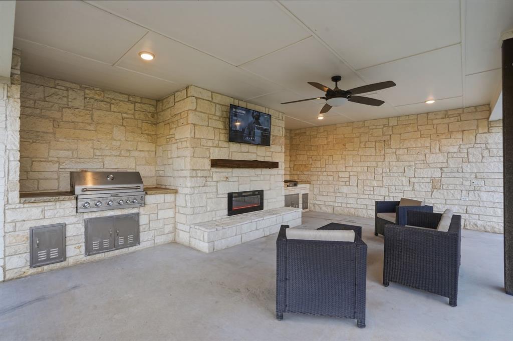 103 Apollo Trail Aurora, TX 76078 - Photo 33 of 40 View of patio featuring a glass covered fireplace, ceiling fan, and an outdoor kitchen with living area
