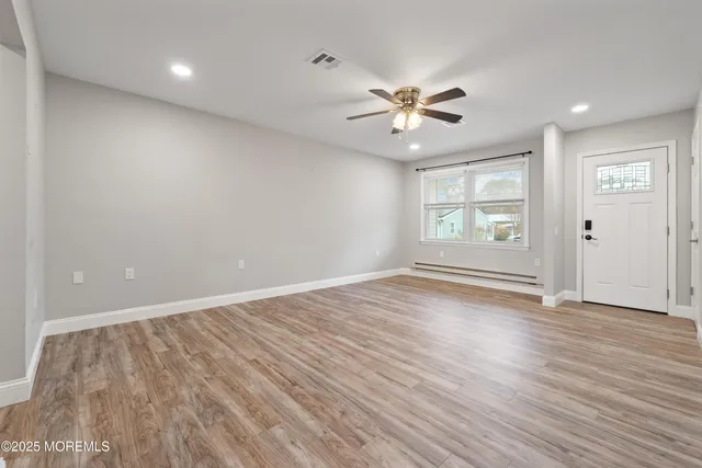 an empty room with wooden floor fan and windows