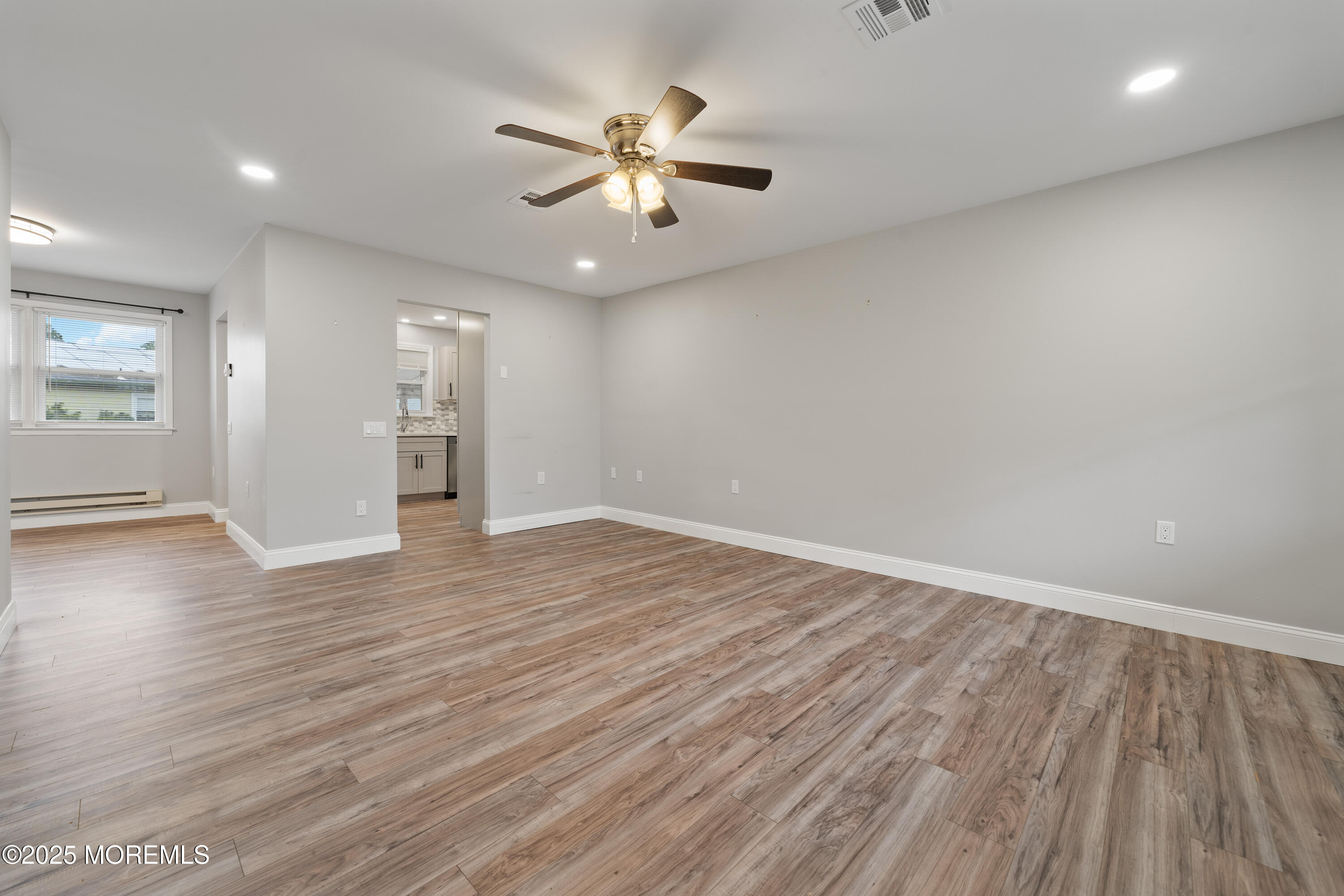 81 Falmouth Avenue, Unit 72 Whiting, NJ 08759 - Photo 5 of 20 an empty room with wooden floor chandelier fan and windows