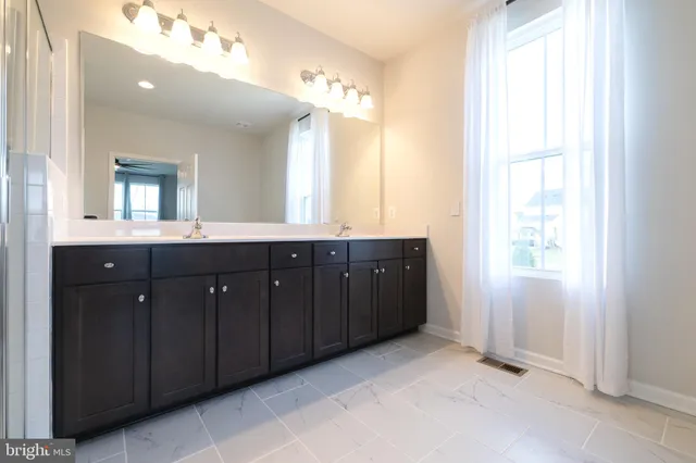a bathroom with a granite countertop sink two mirror and a window