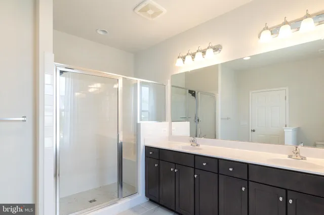 a bathroom with a double vanity sink mirror and shower