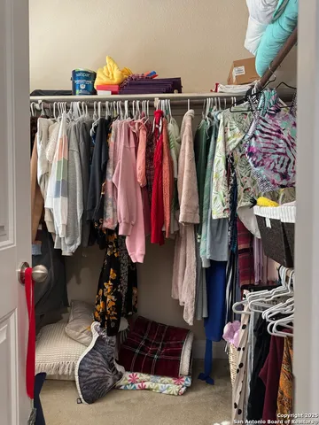 a view of walk in closet with clothes and shoes