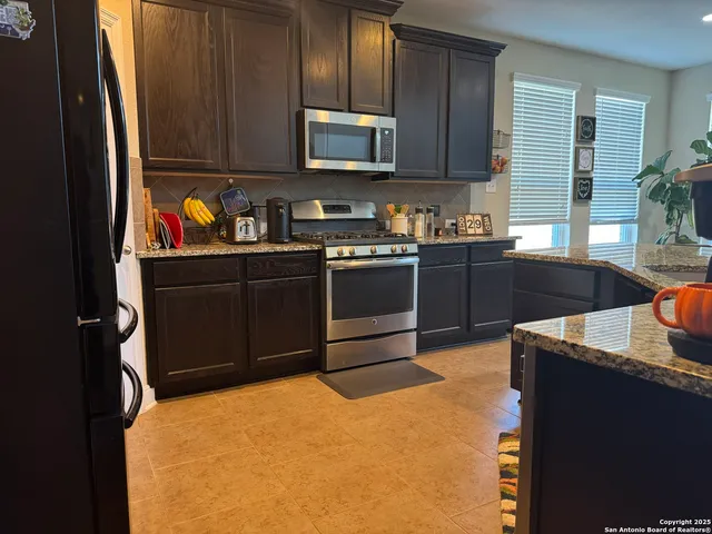 a kitchen with stainless steel appliances granite countertop a stove a sink and a microwave