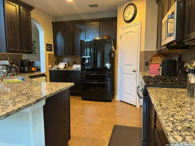 a kitchen with stainless steel appliances granite countertop a refrigerator a stove and a sink