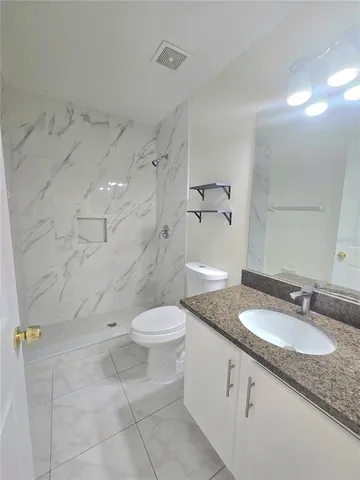a bathroom with a granite countertop sink a toilet and a mirror