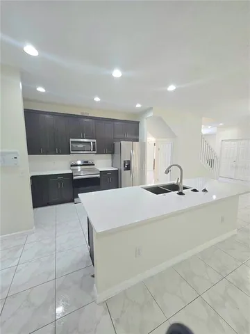 a large kitchen with kitchen island a sink a counter top space and cabinets