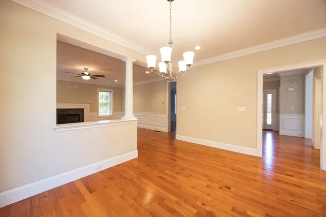 a view of a livingroom with a chandelier fan and wooden floor