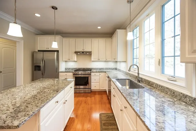 a large kitchen with granite countertop a sink a counter space appliances and cabinets