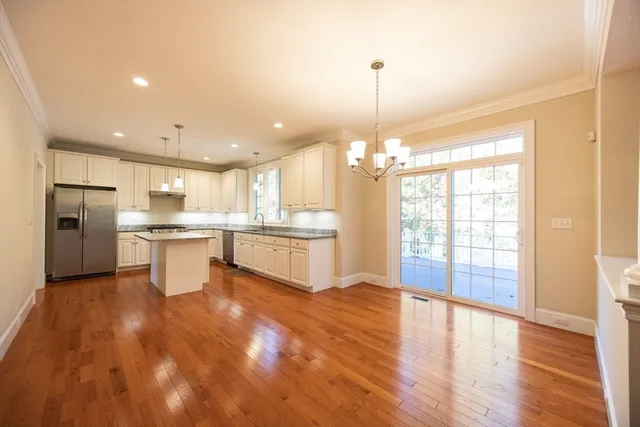 a open kitchen with kitchen island a stove a refrigerator a sink dishwasher and a fireplace with wooden floor
