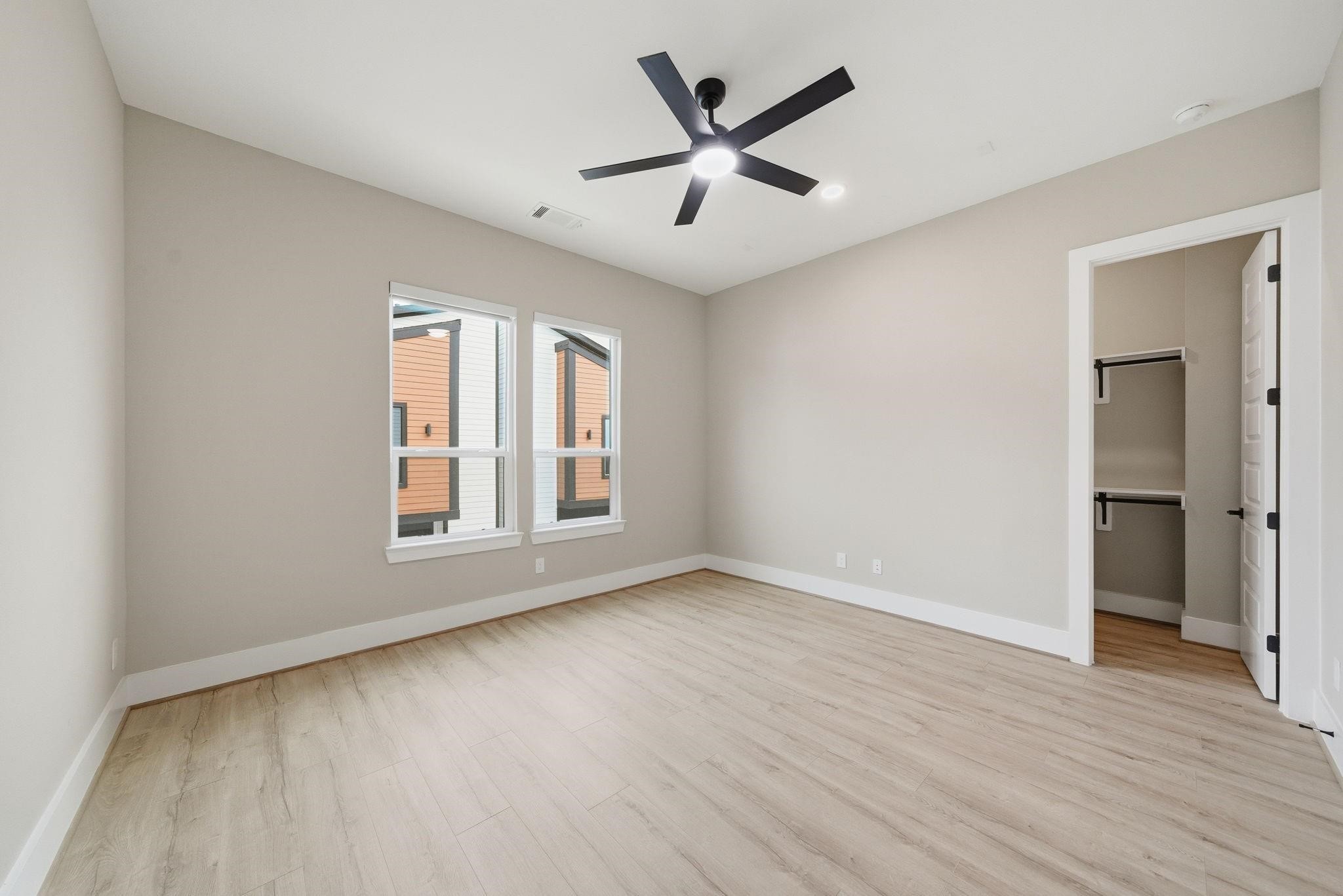 4013 Griggs Road, Unit F Houston, TX 77021 - Photo 16 of 35 Spacious bedroom with elegant hardwood flooring, modern ceiling fan, and ample natural light from large windows, featuring a walk-in closet for added convenience.