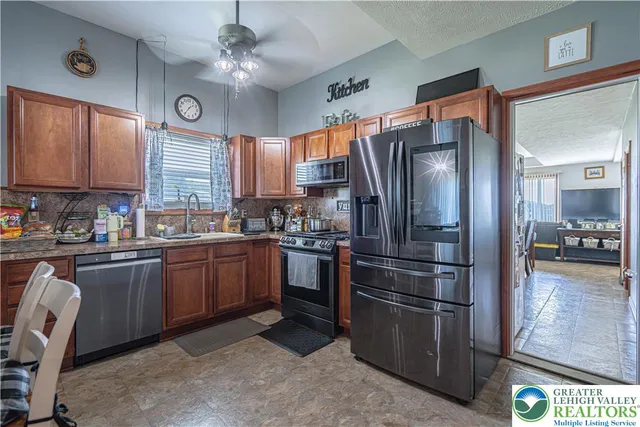 a kitchen with stainless steel appliances granite countertop a refrigerator a stove a sink dishwasher a dining table and chairs with wooden floor