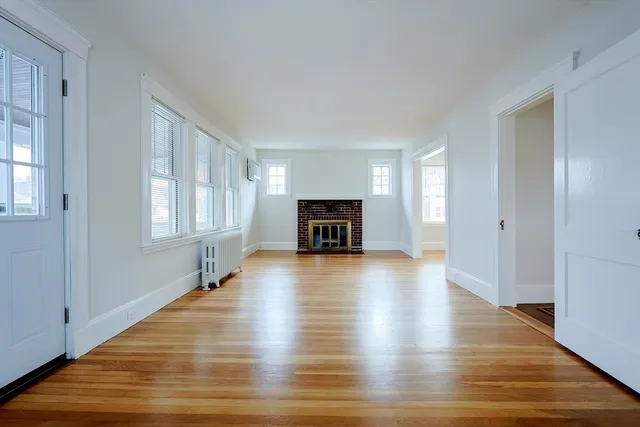 a view of a livingroom with wooden floor and a fireplace