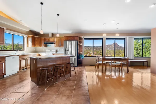 a open kitchen with stainless steel appliances granite countertop a stove top oven a sink a dining table and chairs with wooden floor